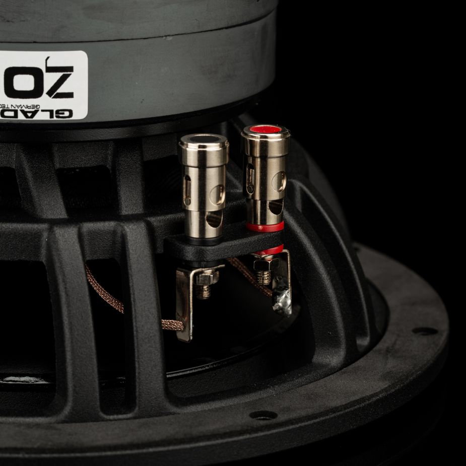 Primer plano de los terminales de conexión del subwoofer del Gladen Zeta 08, con conectores rojos y negros y la inscripción «GLAD», que garantizan unos graves precisos sobre un fondo negro.
