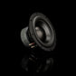 Un subwoofer Gladen Zeta 08 de color negro se encuentra colocado en ángulo sobre una superficie reflectante, lo que resalta su acabado mate y sus terminales para unos graves precisos.