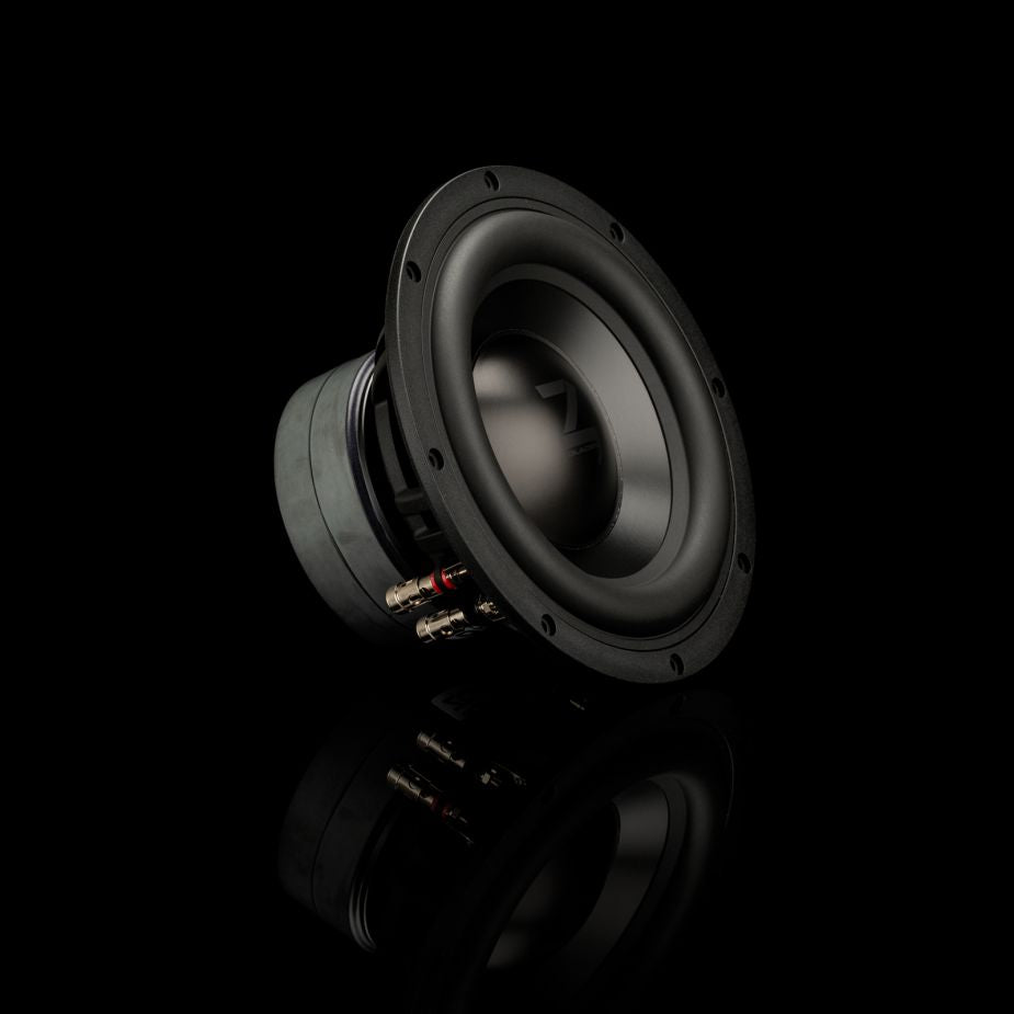 Un subwoofer Gladen Zeta 08 nero è posizionato di traverso su una superficie riflettente, il che mette particolarmente in risalto la sua finitura opaca e i connettori per bassi precisi.