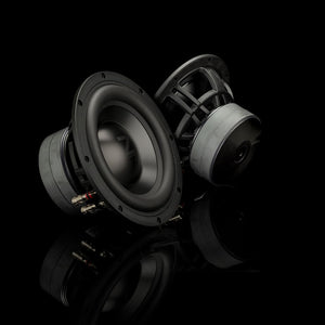 Deux caissons de basses Gladen Zeta 08, réputés pour la précision de leurs basses, trônent sur une surface noire brillante, avec en toile de fond un décor noir saisissant.