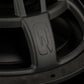 Primer plano del subwoofer Gladen Zeta 10 en color negro, con un logotipo «Q» estilizado en su marco metálico, que destaca por su textura y su potente respuesta de graves.