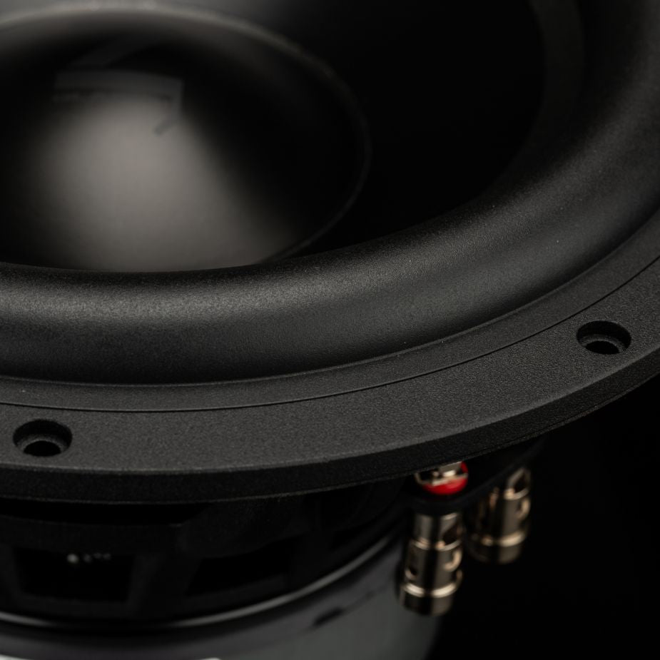 Primer plano del Gladen Zeta 10, un subwoofer negro de 10 en el que se aprecian el borde, los tornillos y los terminales; ideal para graves profundos sobre un fondo oscuro.
