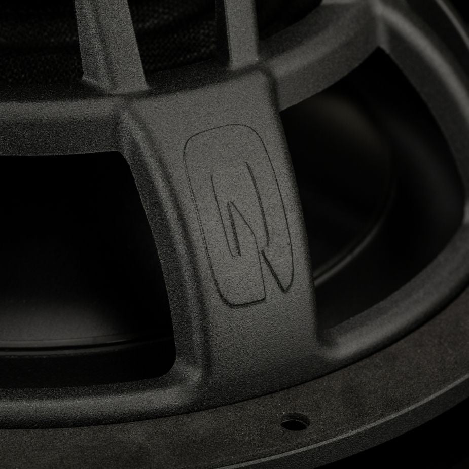 Primo piano del subwoofer Gladen Zeta 10 in nero, caratterizzato da un logo Q stilizzato sul telaio metallico, che ne mette in risalto la texture e la potente risposta dei bassi.