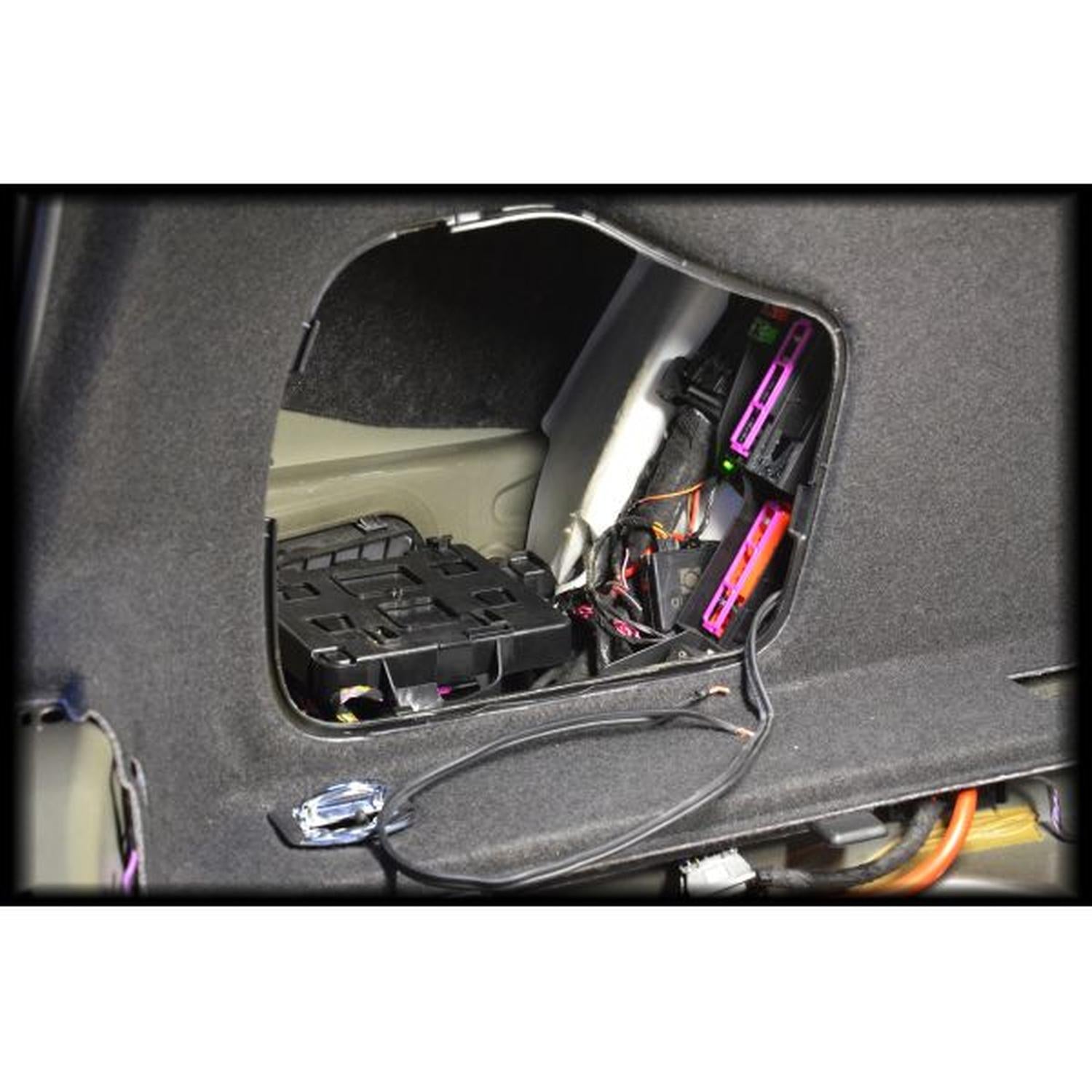 Un primo piano di un pannello aperto dellauto mostra il cablaggio, i fusibili e i componenti dietro le finiture vicino a un subwoofer Masori G10-15 Audi A4 B9 Limousine.