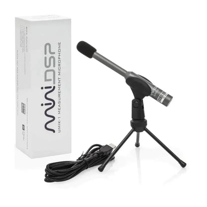 Un microphone de mesure miniDSP UMIK-1 V3, monté sur un petit trépied et muni dun câble USB, est posé à côté dune boîte blanche portant linscription « miniDSP UMIK-1 V3 ».