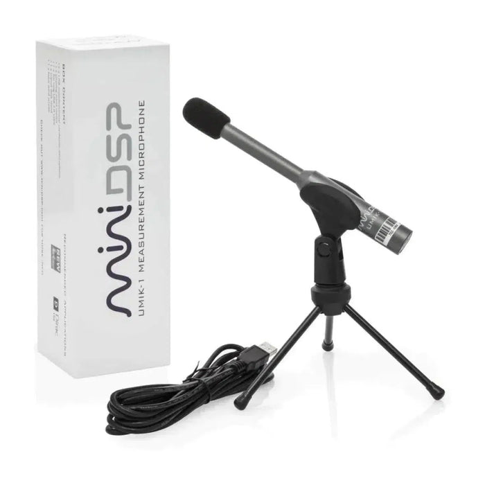 Un microphone de mesure miniDSP UMIK-1 V3, monté sur un petit trépied et muni dun câble USB, est posé à côté dune boîte blanche portant linscription « miniDSP UMIK-1 V3 ».